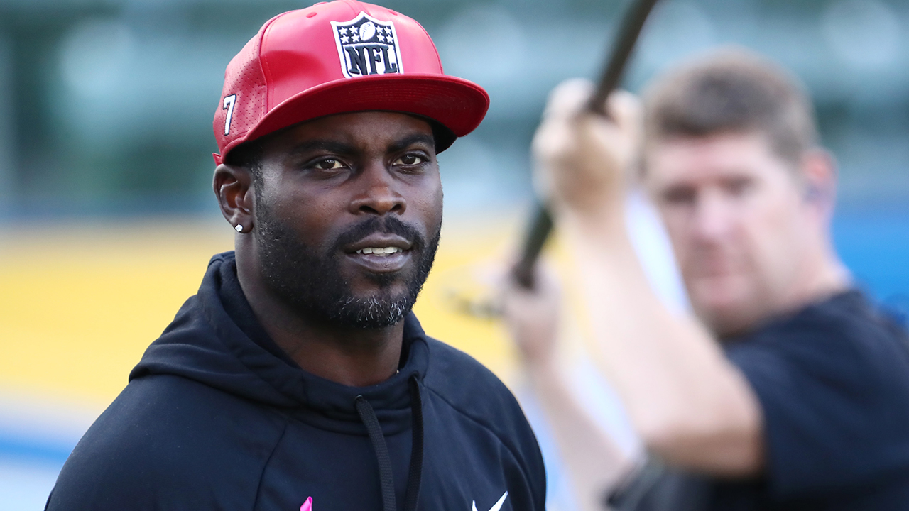 Former Atlanta Falcons and Philadelphia Eagles quarterback Michael Vick  wears one of his special edition New Era hats on sale in the NFL Shop at  the Super Bowl Experience on Thursday, Jan.