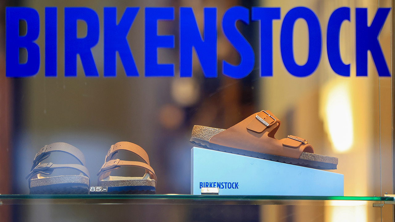 A shopper peruses the Birkenstock sandals displayed in a shoe